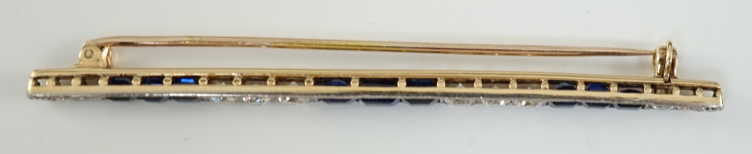 An Art Deco, round cut diamond and rectangular cut sapphire cluster bar brooch